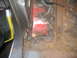 1983 Ford F-250 - Close-up view of a rusted and repaired metal floor pan, showing welding marks and red undercoating.