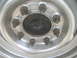 1983 Ford F-250 - A silver wheel hub with eight rusty lug nuts is shown, with a black center cap visible.