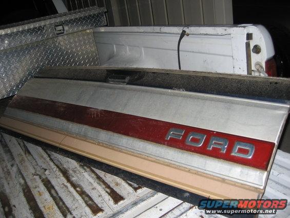 Ford tailgate panel with red stripe and chrome letters, sitting in a truck bed