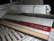 1983 Ford F-250 - A Ford tailgate panel with a red stripe and chrome lettering is stored in the bed of a pickup truck.