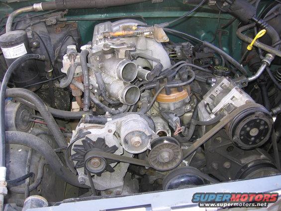 Engine bay with V8 engine, distributor, alternator, and AC compressor visible