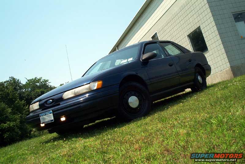 1993 Ford Taurus sedan parked on a grassy slope next to a building