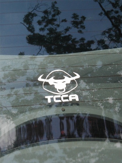 White bull logo with text 'TCCA' below it, on a blurred background