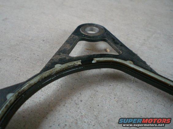 Damaged engine gasket with torn sealing material on a concrete surface