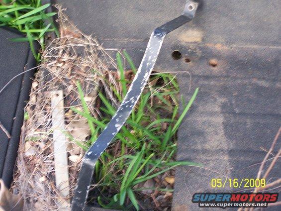 metal bracket on a dark surface with grass growing through gaps