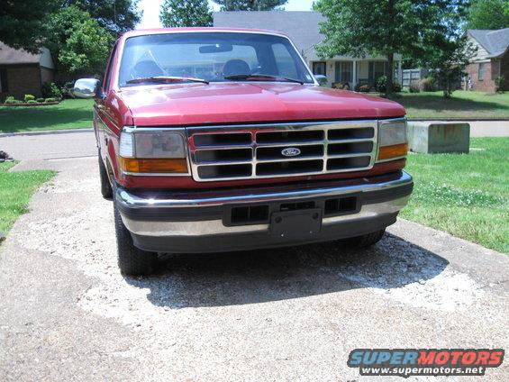 Red 1996 Ford F-150 parked on a gravel driveway, front view