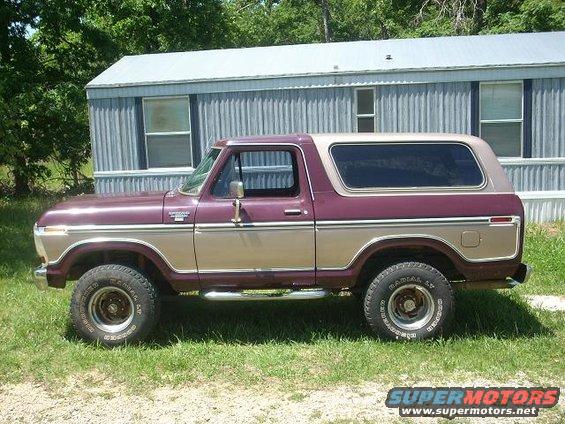 Maroon and tan Ford Bronco SUV parked on grass in front of a mobile home