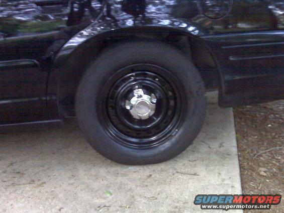 2001 Ford Crown Victoria rear wheel and fender, black paint, steel wheel with chrome center cap