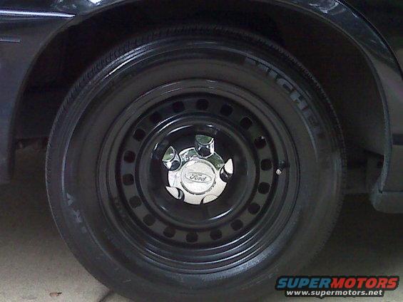 Black steel wheel with a chrome Ford hubcap on a 2001 Ford Crown Victoria
