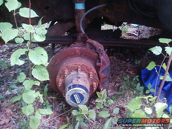 Close-up of a rusty wheel hub with a blue WARN decal, part of a vehicle's suspension system
