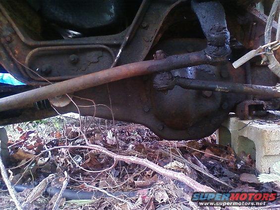 Undercarriage of a rusty vehicle with visible steering components and differential