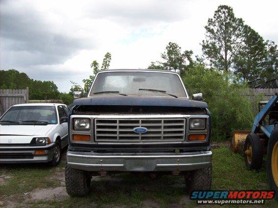 Front view of a dark blue Ford F-Series truck parked next to a white car. Another piece of equipment is to the right