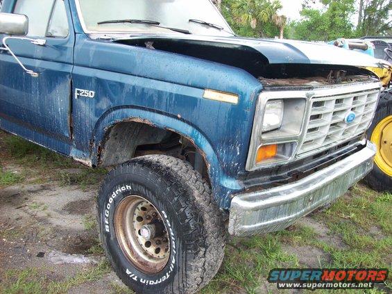 Blue Ford F-250 truck with rust on the fender and hood ajar, showing a chrome bumper and BFGoodrich tires