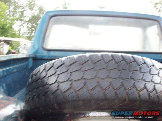 Spare tire lying flat in the bed of a blue pickup truck