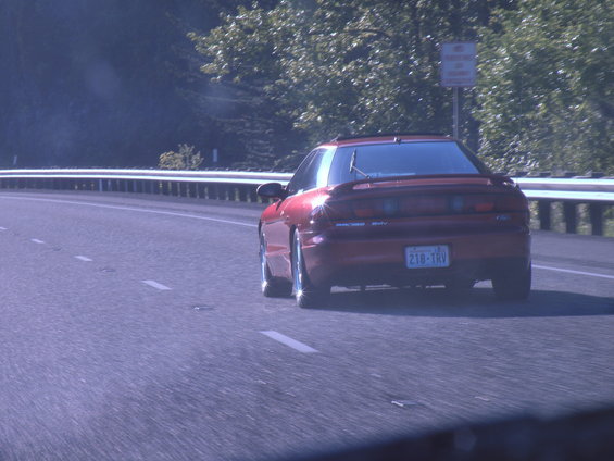 Red coupe with license plate 218-TRV driving on a highway