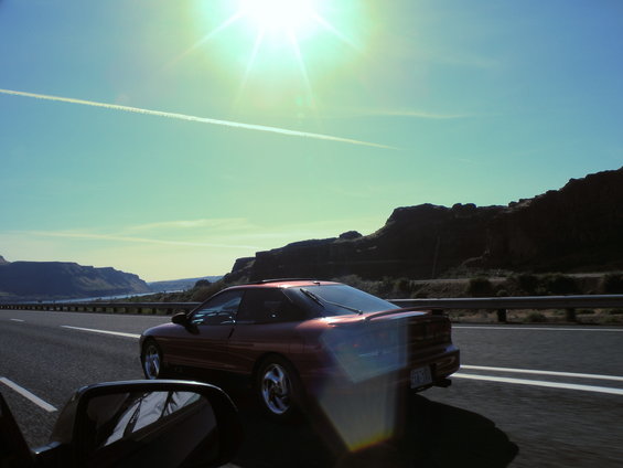 Red 1989 Nissan 300ZX coupe driving on a highway with mountains in the background
