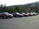 1989 Nissan 300ZX - A group of sports cars are lined up in a parking lot with a mountain and trees in the background.