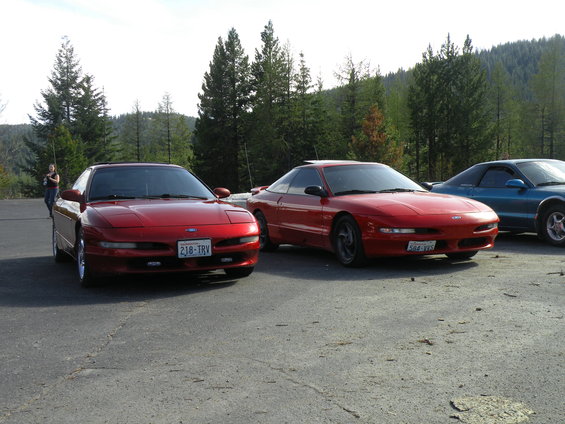 Two red Ford Probes, one with license plate 218-TRV, parked on asphalt