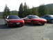 1989 Nissan 300ZX - Two red Ford Probes are parked on an asphalt surface with a wooded hillside in the background.
