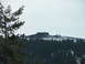 1989 Nissan 300ZX - A building sits atop a hill covered in snow and rocks, with a thick forest below under a pale sky.