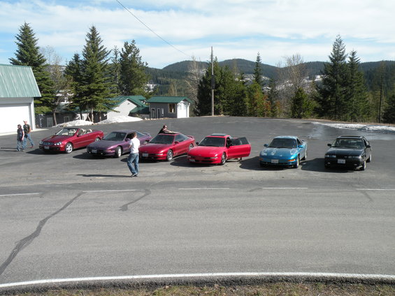 Several sports cars parked in a lot with a mountainous backdrop