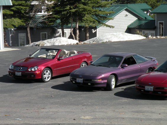 Red convertible, purple coupe, and red coupe parked in a lot