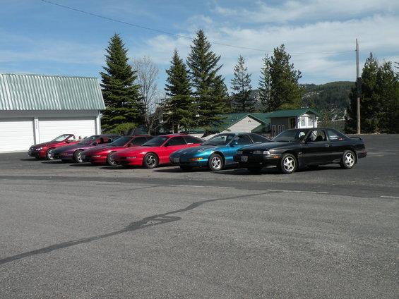 Several sports cars parked in a row, including a black coupe and a blue coupe