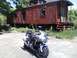 2006 Suzuki SV1000S - A silver 2006 Suzuki SV1000S motorcycle is parked in front of an old, red caboose.