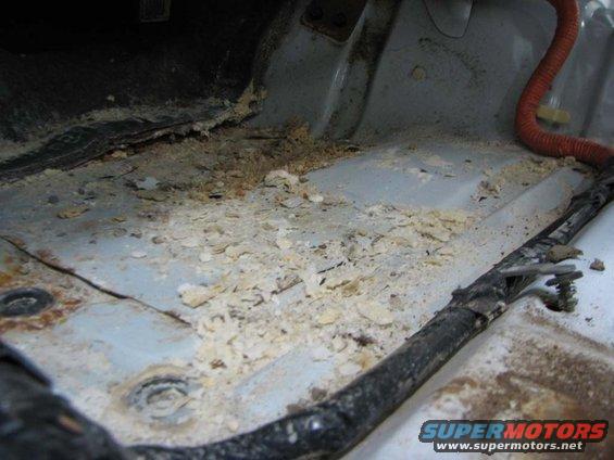 Corroded car floor with debris and wiring. Supermotors.net logo visible