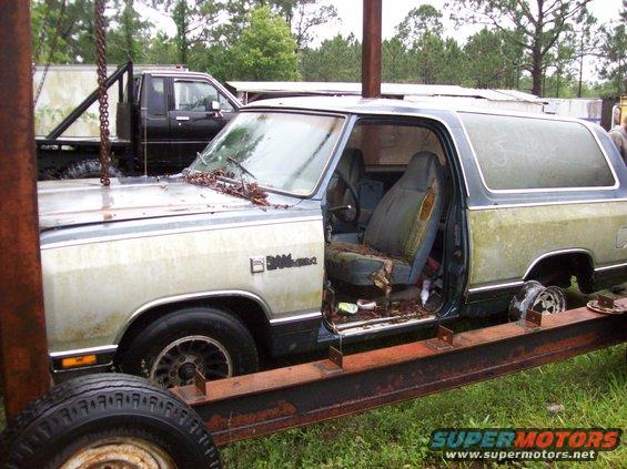 Two-tone Dodge Ramcharger with driver's door open, interior visible, resting on a trailer