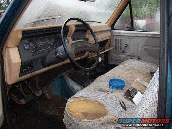 Interior view of a worn truck cab, showing ripped seat and dashboard
