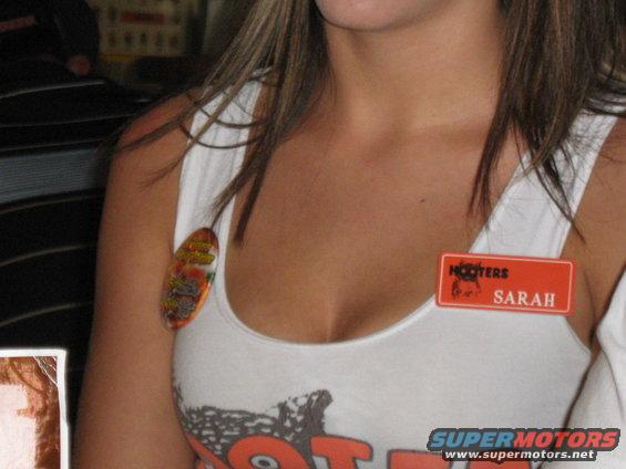 Woman with Hooters name tag reading SARAH on her white tank top