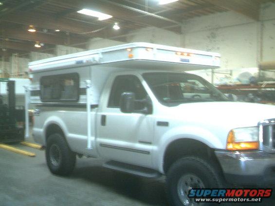 White 2000 Ford F-250 pickup truck with a white camper shell, parked indoors