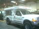 2000 Ford F-250 - White 2000 Ford F-250 pickup truck equipped with a camper shell is parked inside a building.