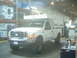 2000 Ford F-250 - A white Ford pickup truck equipped with a camper shell is parked inside a warehouse, with storage shelves in the background.