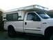 2000 Ford F-250 - This 2000 Ford F-250 pickup truck is equipped with a white camper shell, seen from the side.