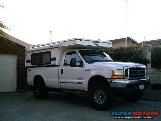 White pickup truck with a camper shell parked in a driveway