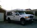 2000 Ford F-250 - Pickup truck with a camper shell parked in front of a garage.