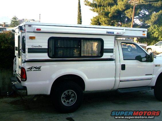White 2000 Ford F-250 pickup truck with a Grandby camper shell, side view