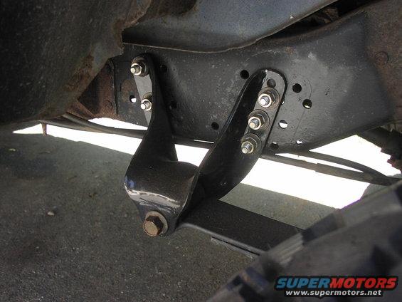 Leaf spring hanger bracket bolted to frame rail, with part of a tire visible