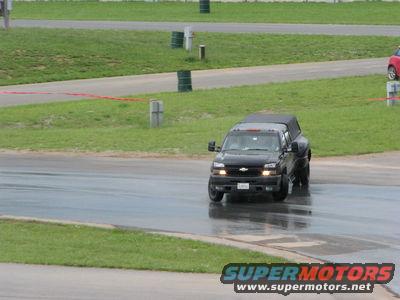 Black pickup truck driving on a wet track