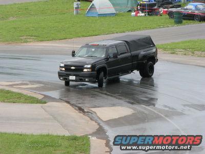 Black pickup truck with a black soft tonneau cover driving on a wet road