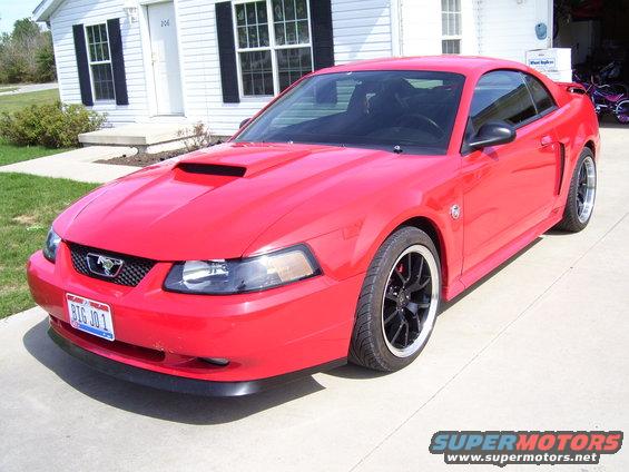 Red 2004 Ford Mustang coupe with a hood scoop and black wheels parked on a driveway