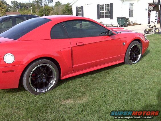 Red 2004 Ford Mustang parked on a grassy lawn in front of a house