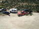 1986 Ford Bronco - A group of off-road vehicles are gathered on a dusty trail in a hilly, arid environment.
