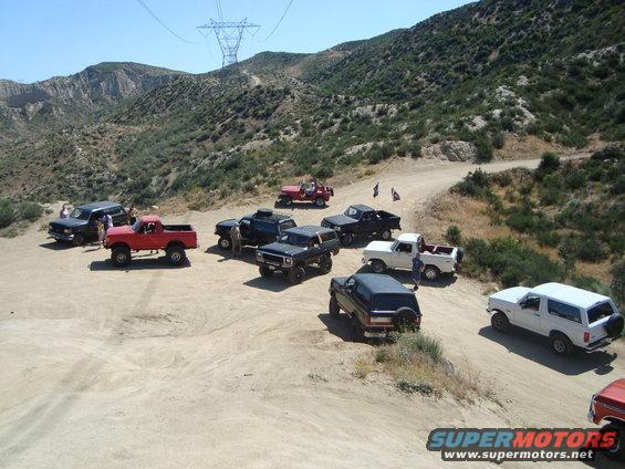 1986 Ford Bronco parked with other off-road vehicles on a dirt road