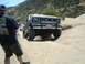 1986 Ford Bronco - A lifted Ford Bronco navigates a sandy off-road path with a person watching.