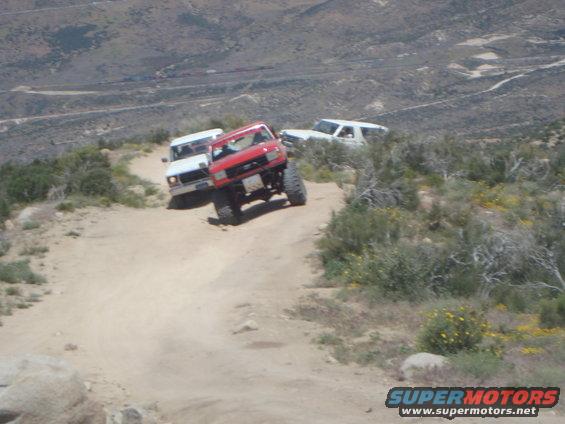 Red and white SUVs driving on a dusty mountain trail