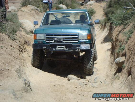 Green SUV with winch on rocky trail, license plate 5ZPW128