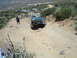 1986 Ford Bronco - A group of off-road vehicles tackle a challenging dirt path on a sunny day.